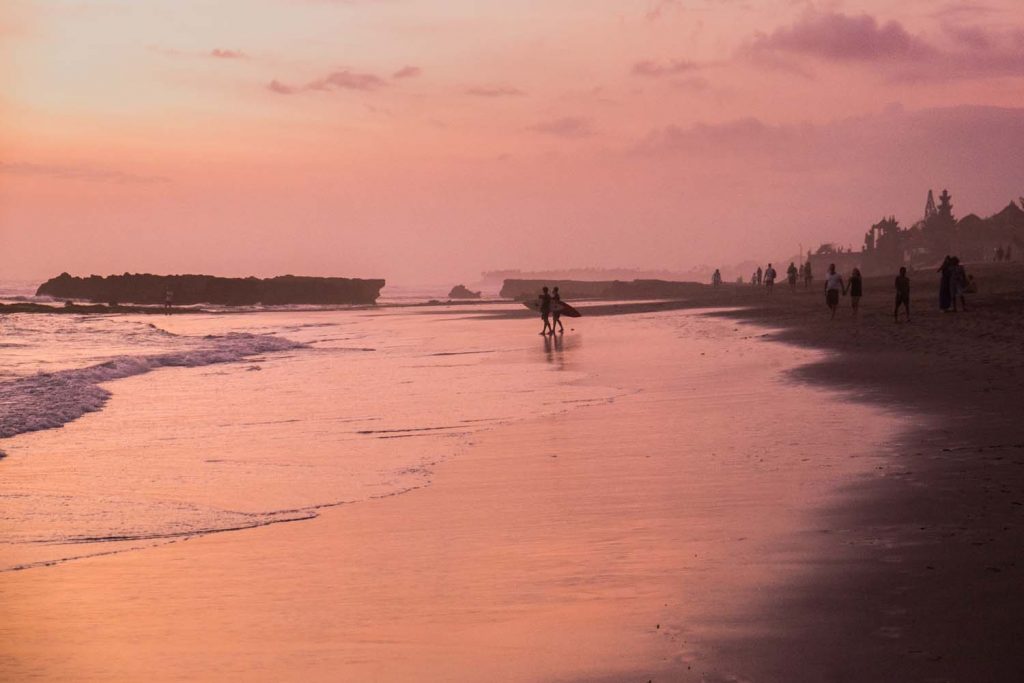 Pink sunset on Echo beach in Bali with surfers
