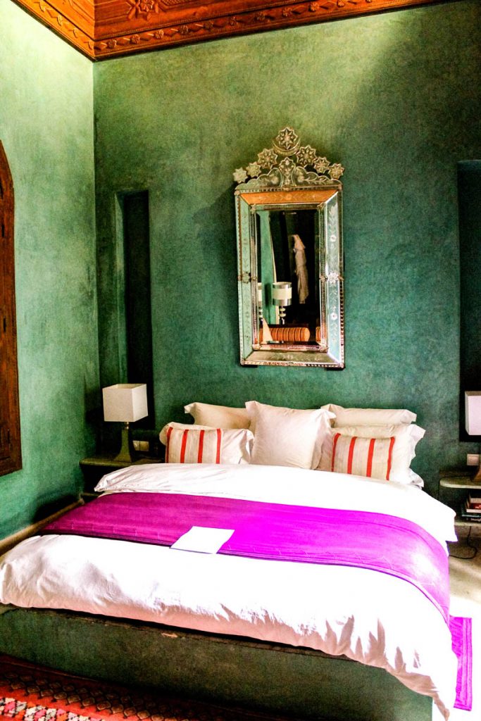 Bed with pink throw in front of a turquoise wall at El Fenn