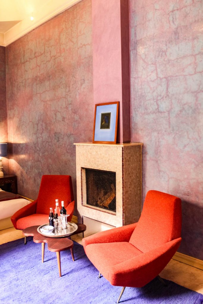 Room with two orange chairs in front of fireplace at El Fenn in Marrakech