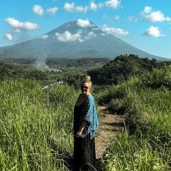 Annika Ziehen standing in a field with Mount Agung in the background