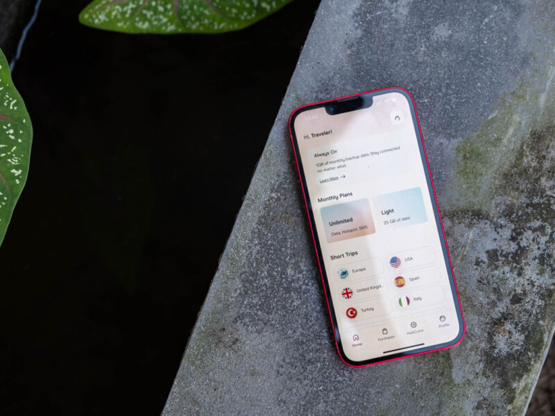 Phone with Holafly eSIM app on concrete next to water