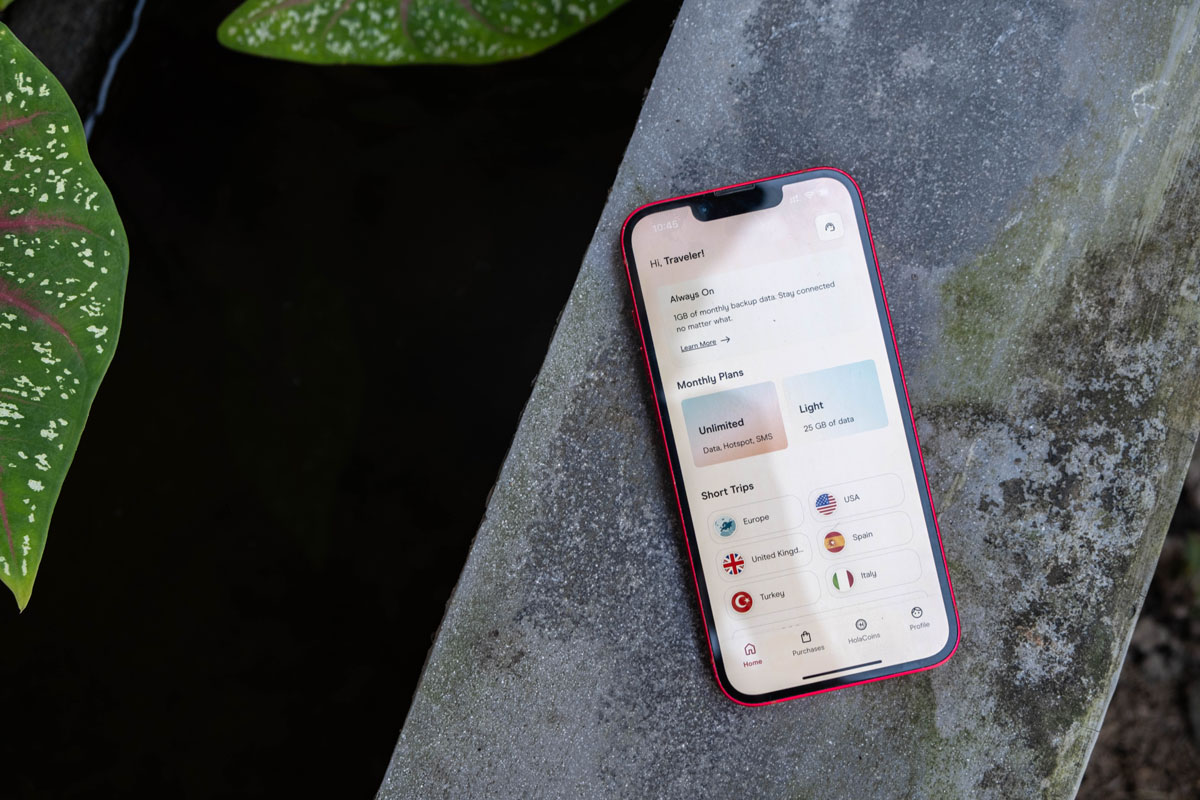 Phone with Holafly eSIM app on concrete next to water